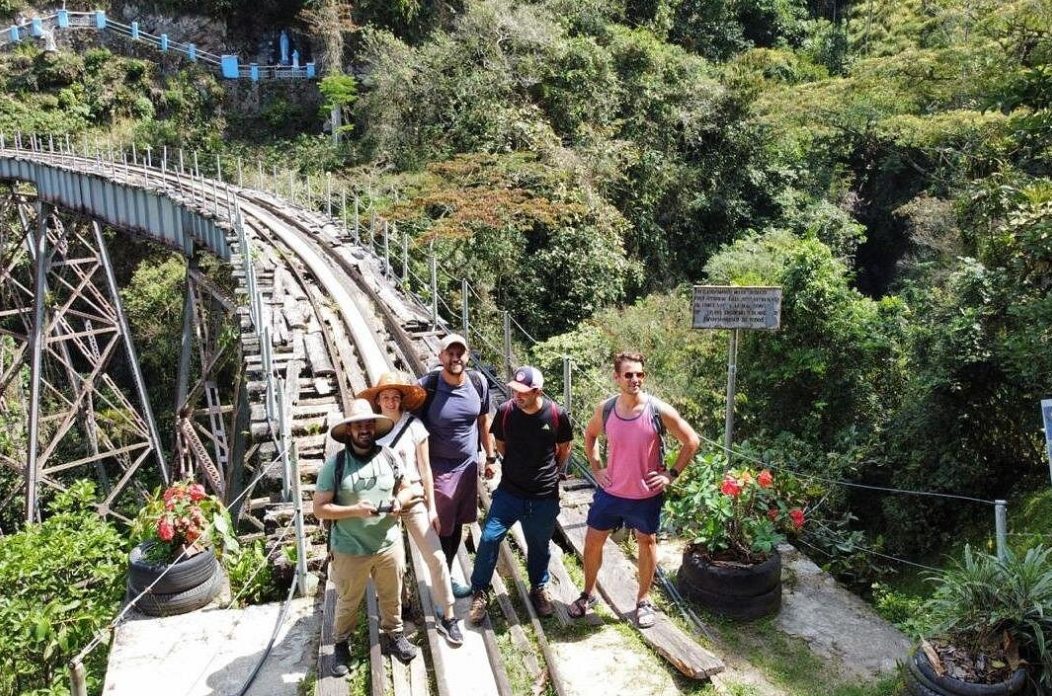 Hikers crossing a historic railway bridge through the misty forest in Amagá